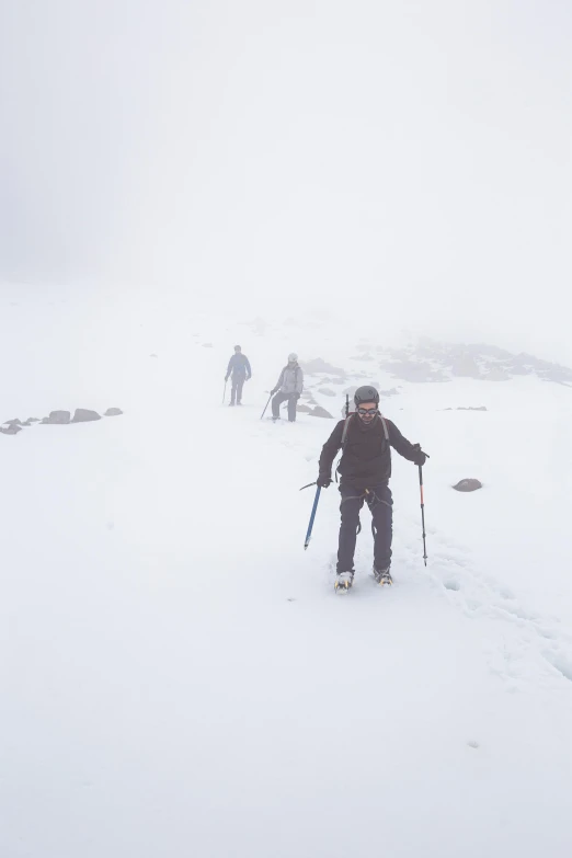 a few snow skiers out in the fog and clouds