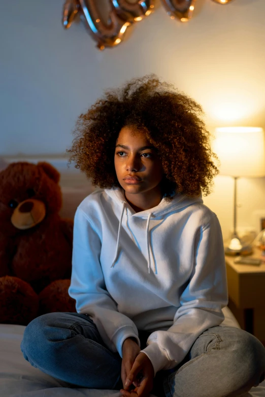 a black woman sitting on a bed with a teddy bear