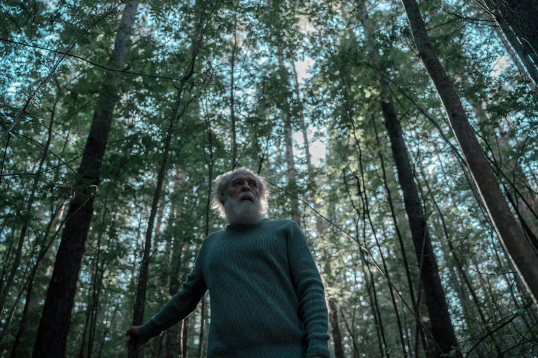 a man is looking up into the air while standing in a forest