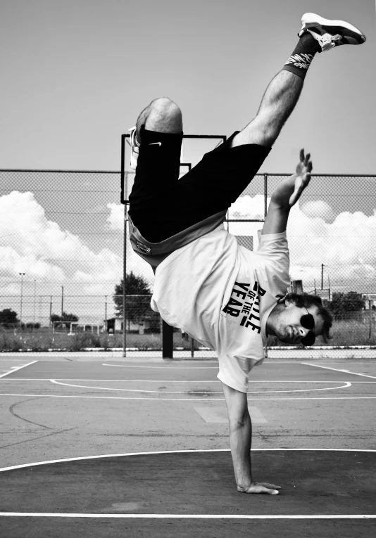 man in black shirt doing a handstand on basketball court