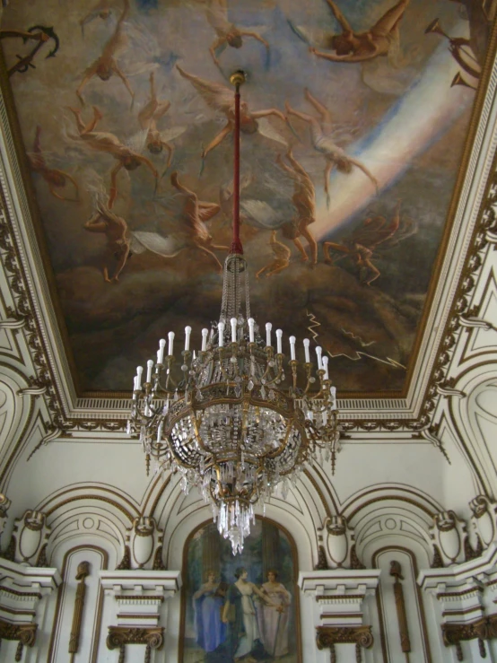 the chandelier is hanging in front of a painting
