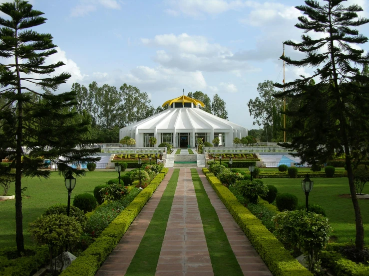 an elegant white gazebo sits in a park with pine trees