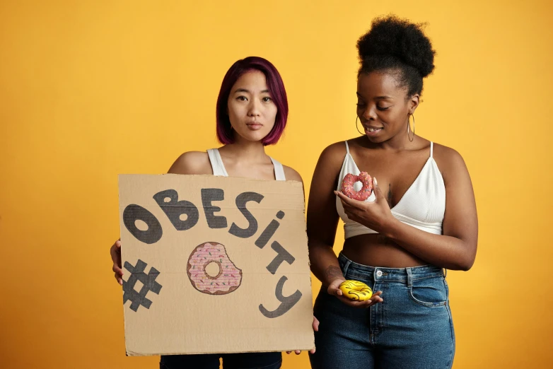 two young women with signs that read 8, 663 donuts