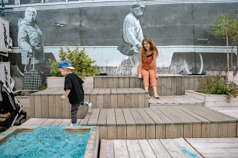 a  and a woman sit on steps in front of a mural