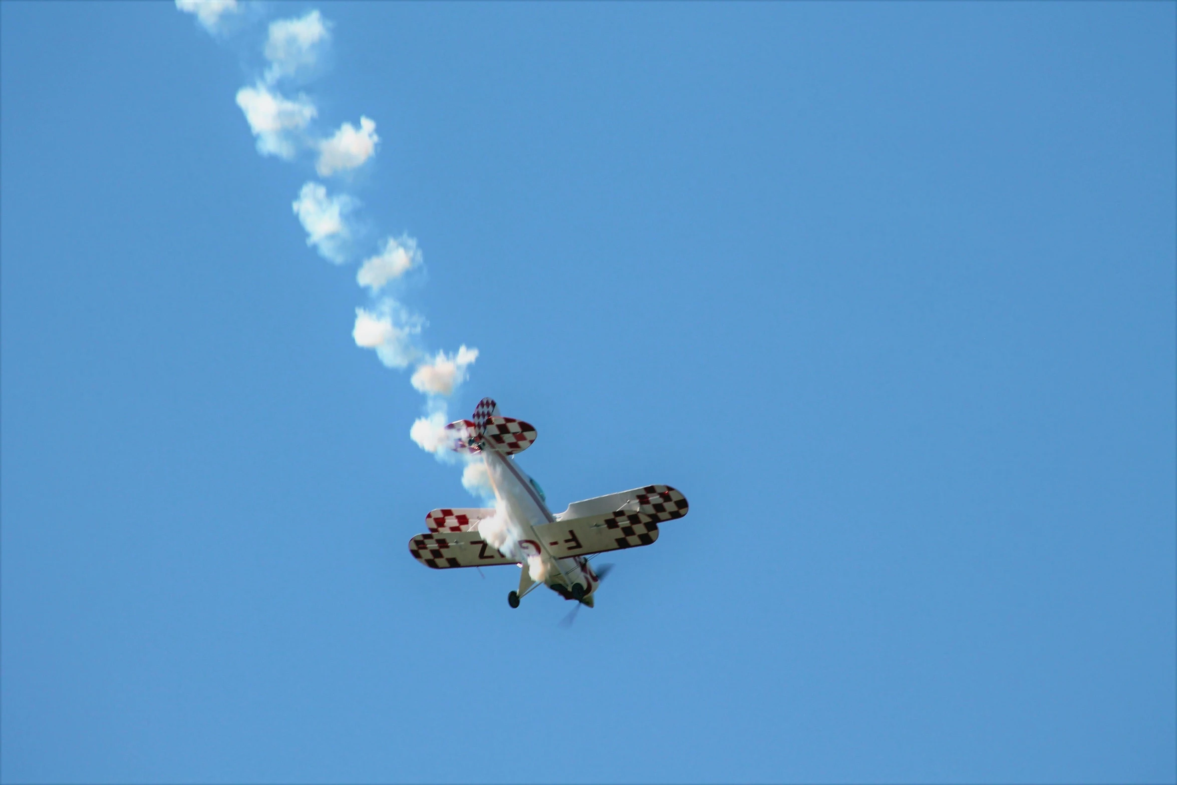 a small plane flying through the air with smoke coming out of it