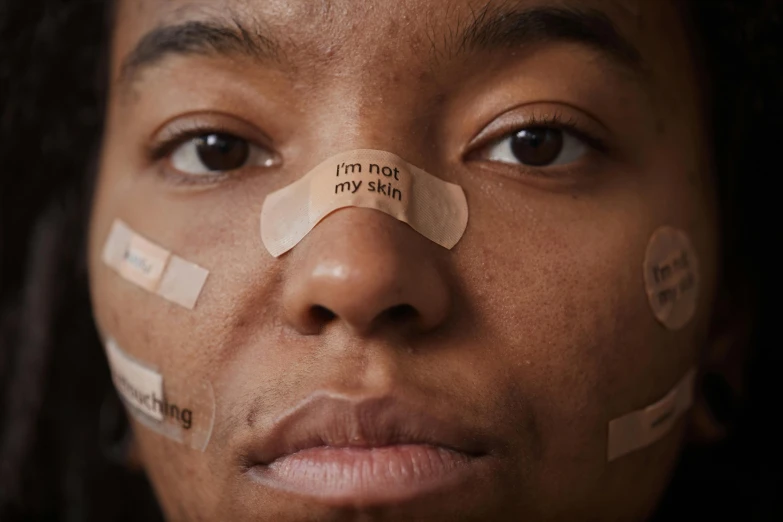 a woman with tape over her nose has ad taped to her cheek