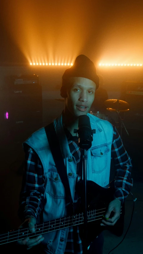 a man holding a guitar while singing into a microphone