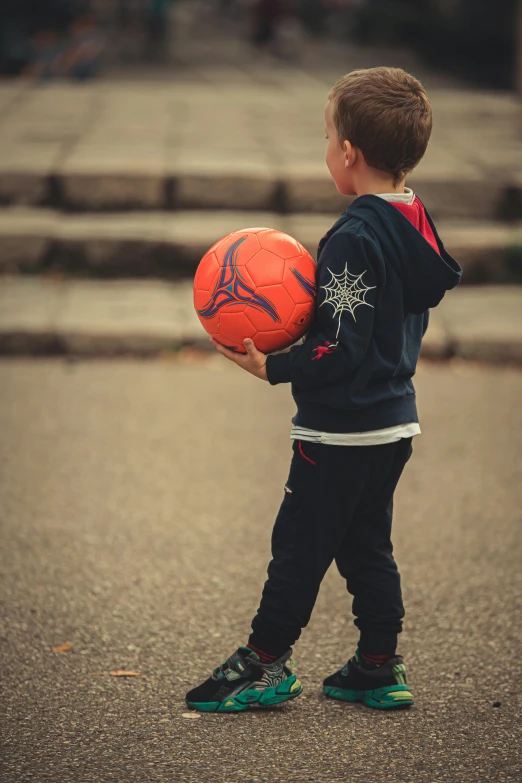  holding a ball outside on the side walk