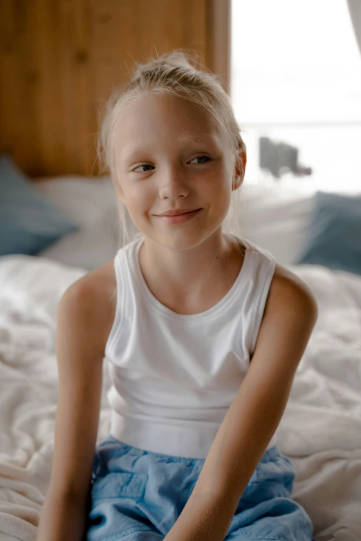 a girl with blonde hair sitting on a bed