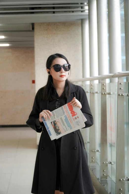 a lady with black sunglasses holds her newspaper