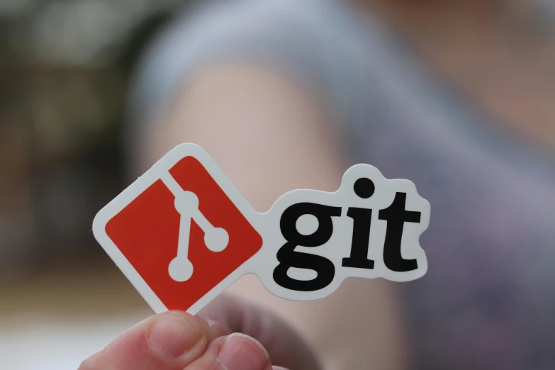 a close up of someone holding a sticker with the word git in it