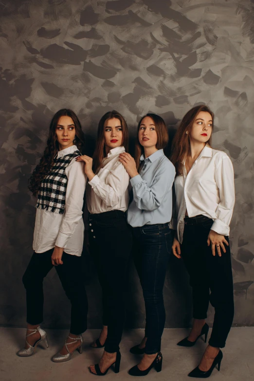 three models standing in front of a gray wall wearing black pants