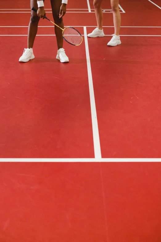 two tennis players stand on a red court