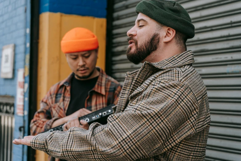 two men stand outside of a building holding tools