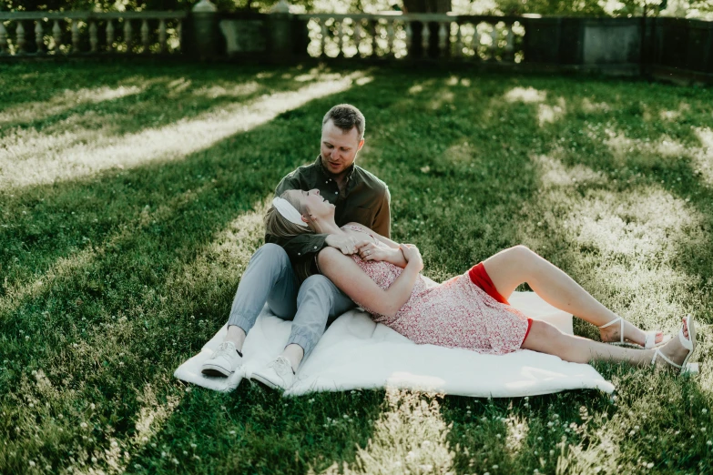 a couple on a towel in the grass in the shade