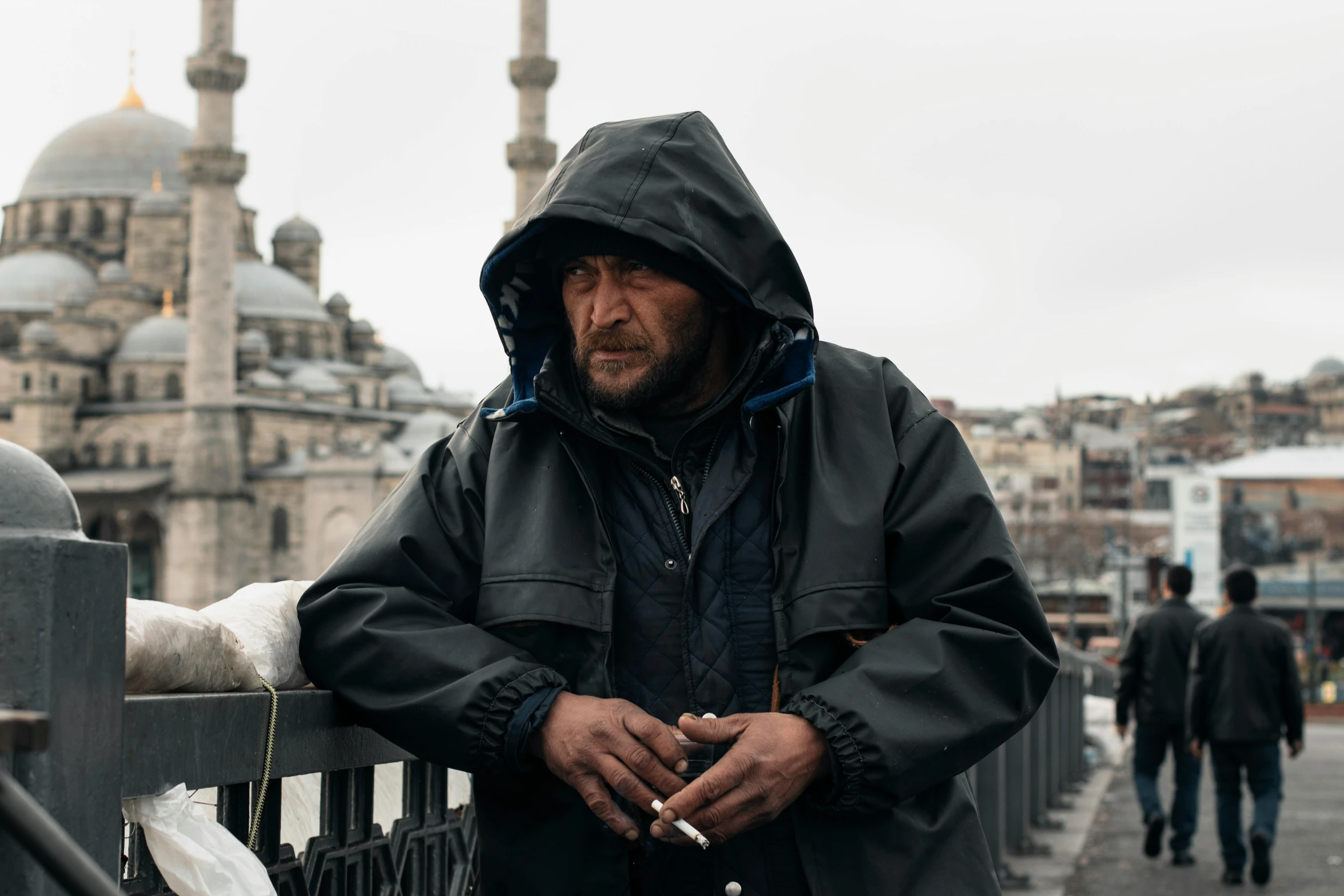 a man stands near an empty bridge in a black jacket