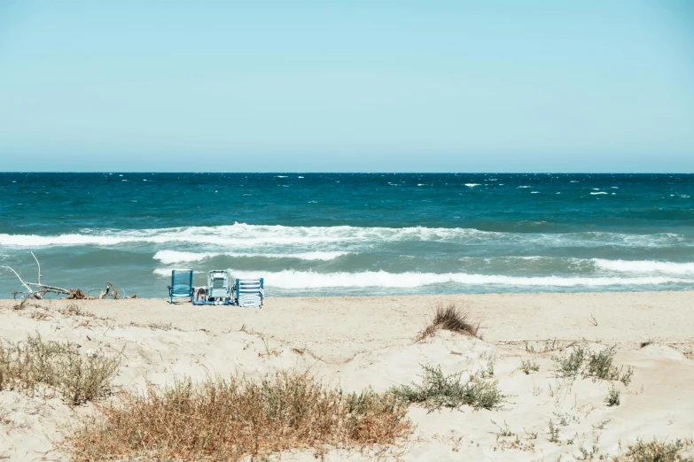 chair sitting on the beach in the sand with the ocean waves rolling around