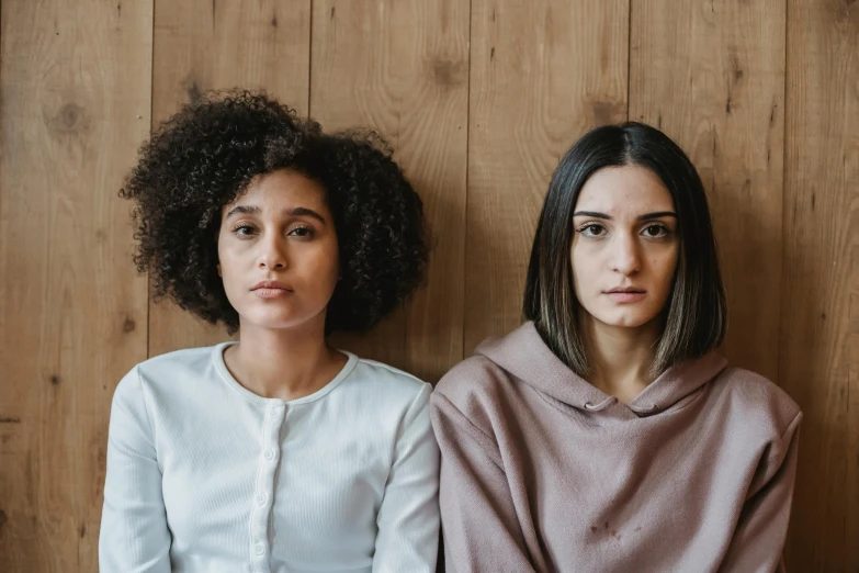 two women sitting on a wooden floor looking off into the distance