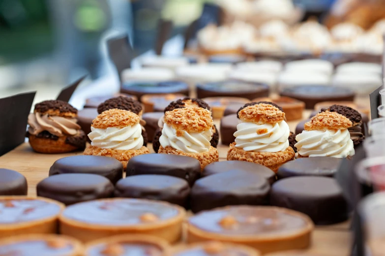 many desserts on a wood tray with one of them is chocolate, and the other is donuts