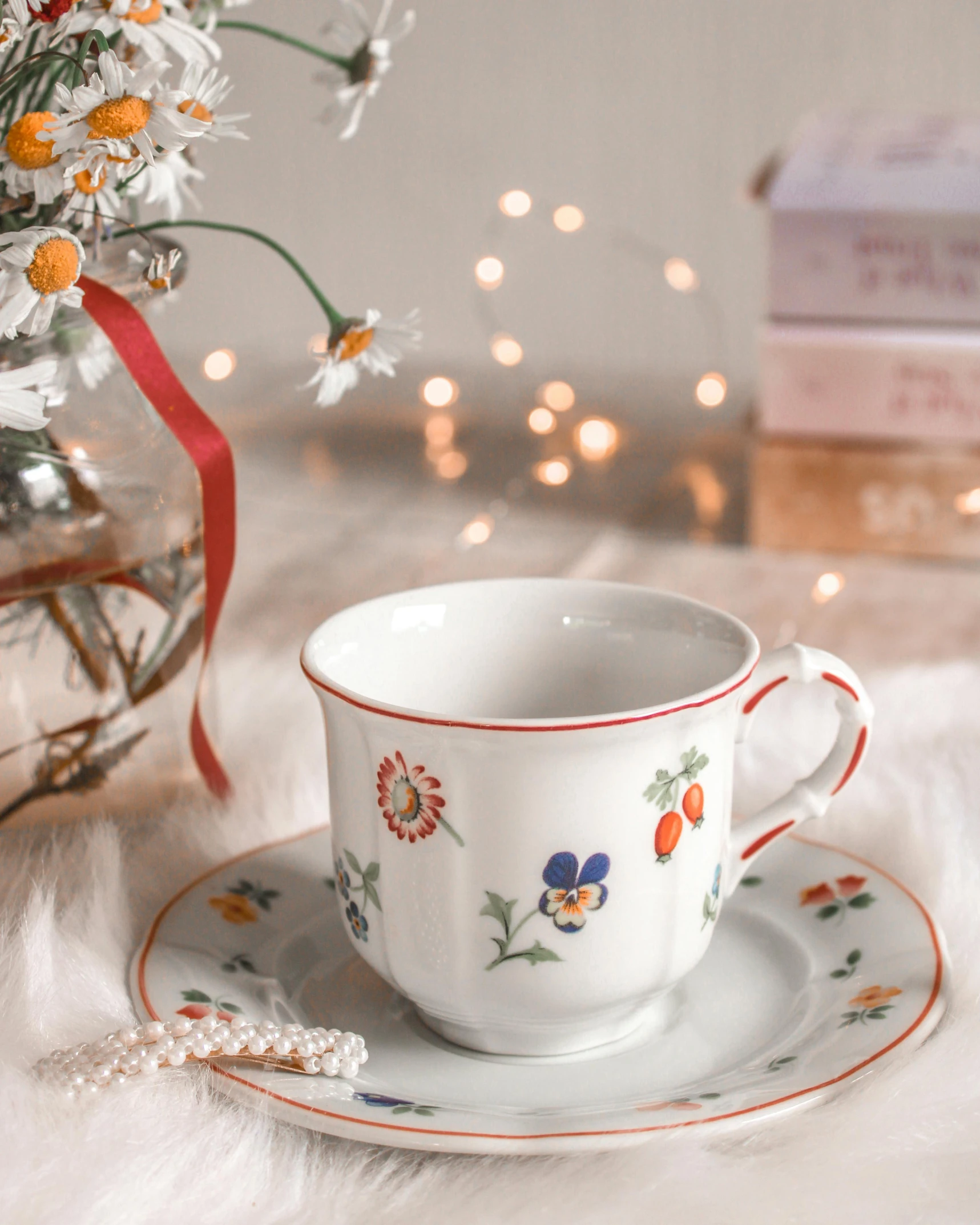 a cup and saucer with flowers and a ribbon tied around it
