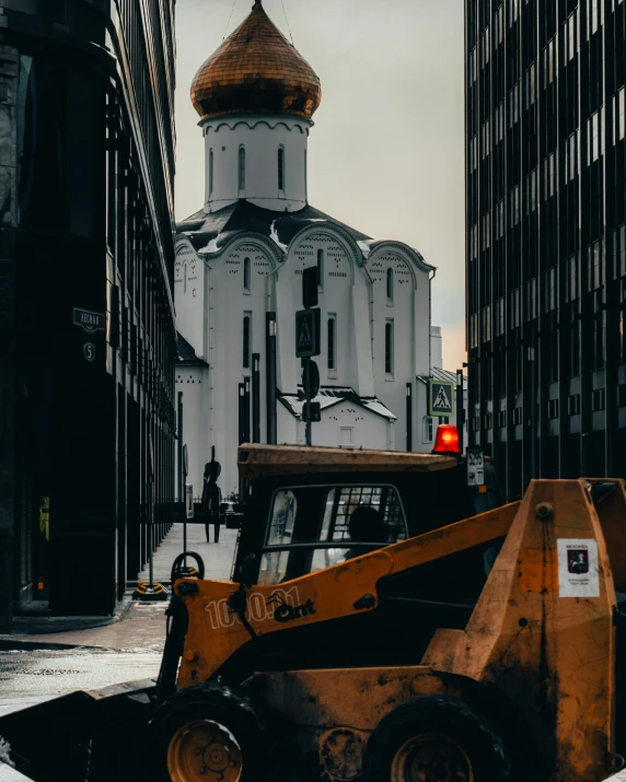 a large yellow backhoe is seen near the tall buildings