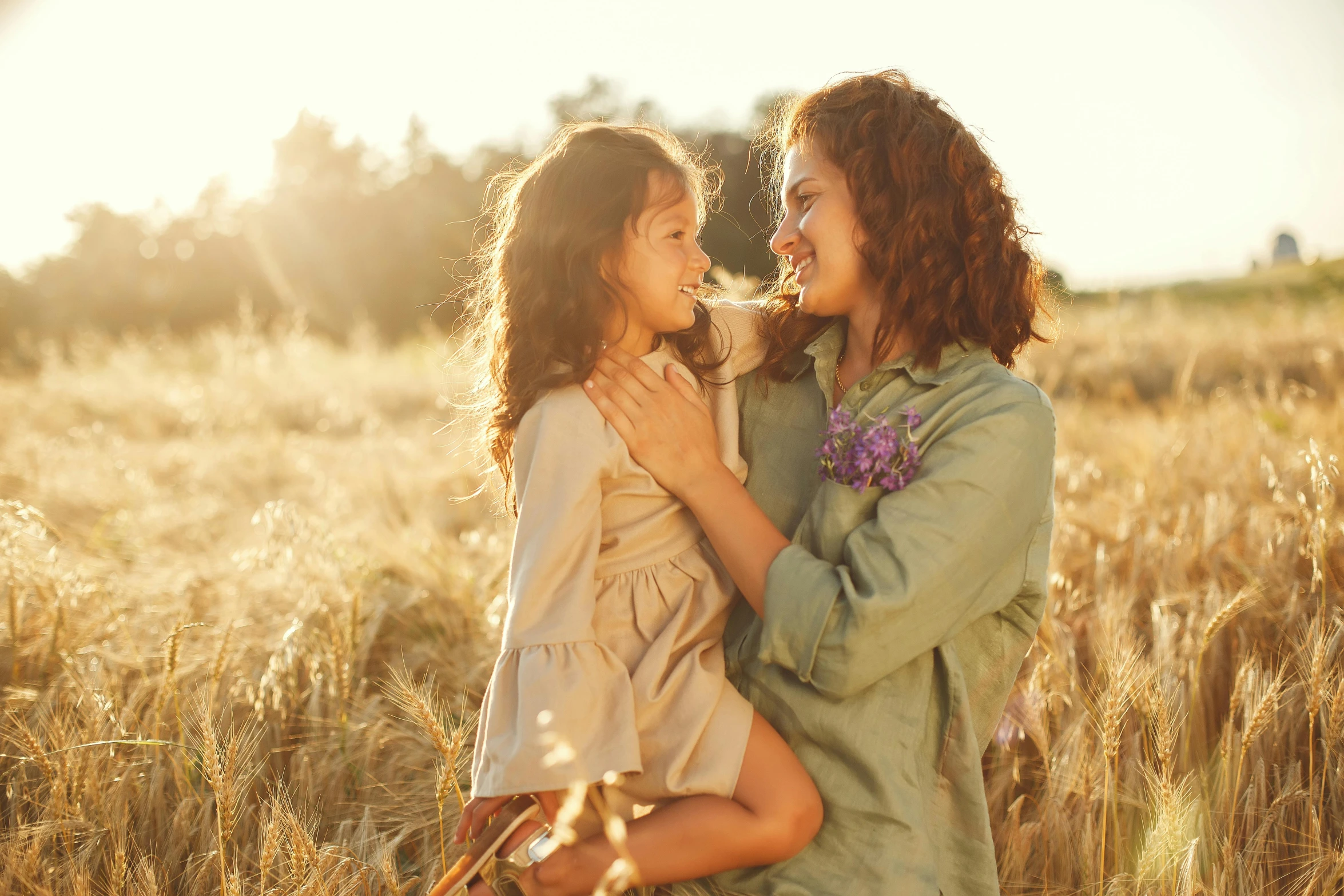 two young women are smiling in a wheat field