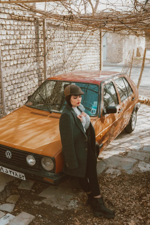 a woman is standing next to a car in front of a brick building