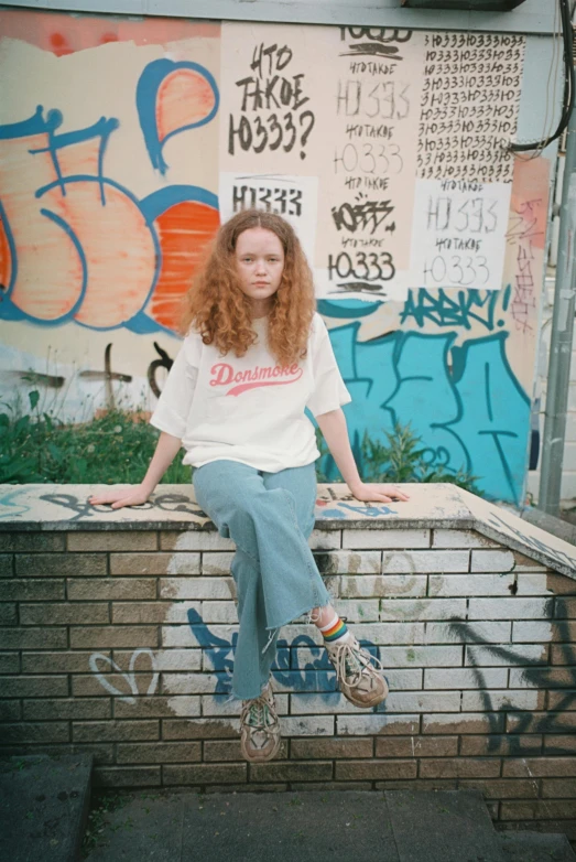 a woman sitting on a ledge near graffiti