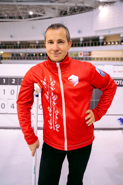 a man standing in an empty building wearing a red jacket