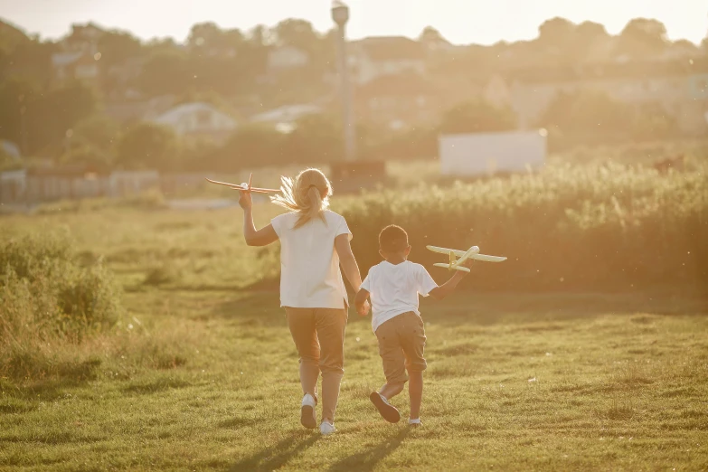 mother and son walking in grassy field with their kites