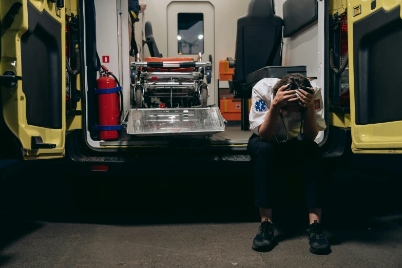 a man sitting in the back of an ambulance holding his hands