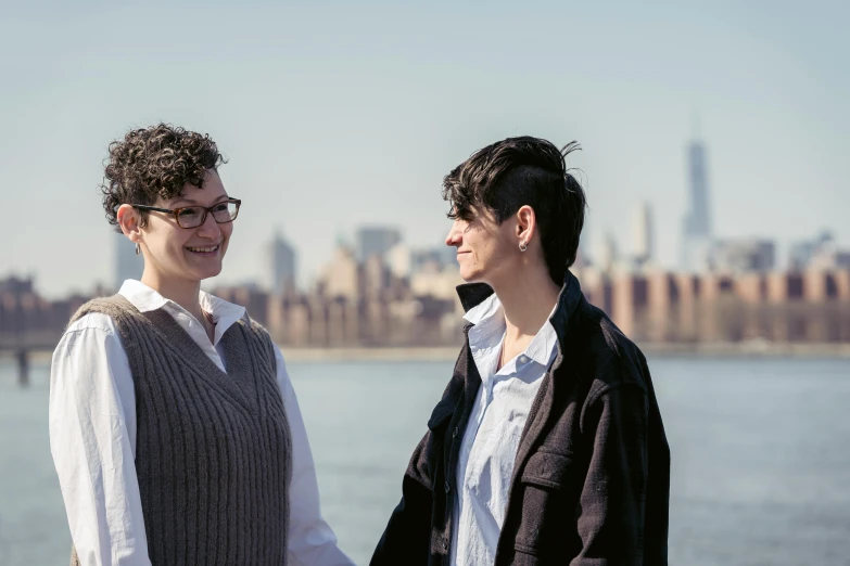 a woman shakes hands with another woman near the water