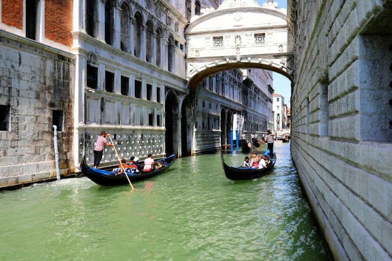 two gondola boats with people on them and arch above them