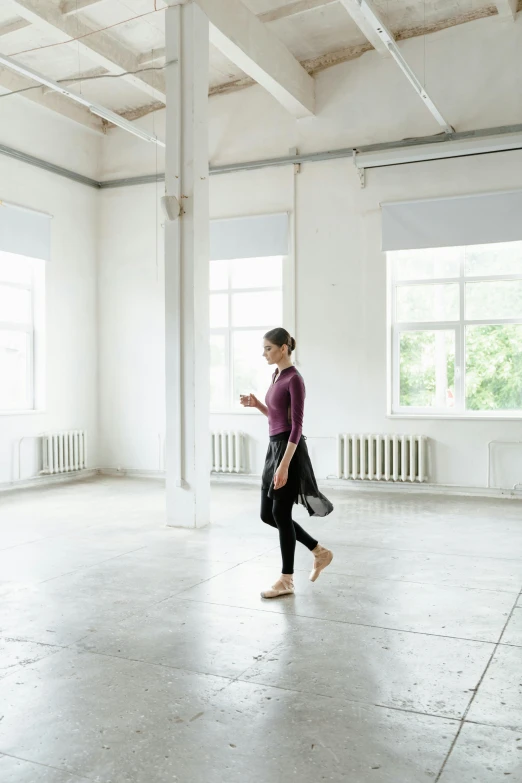 woman in dark clothing walking inside a white room