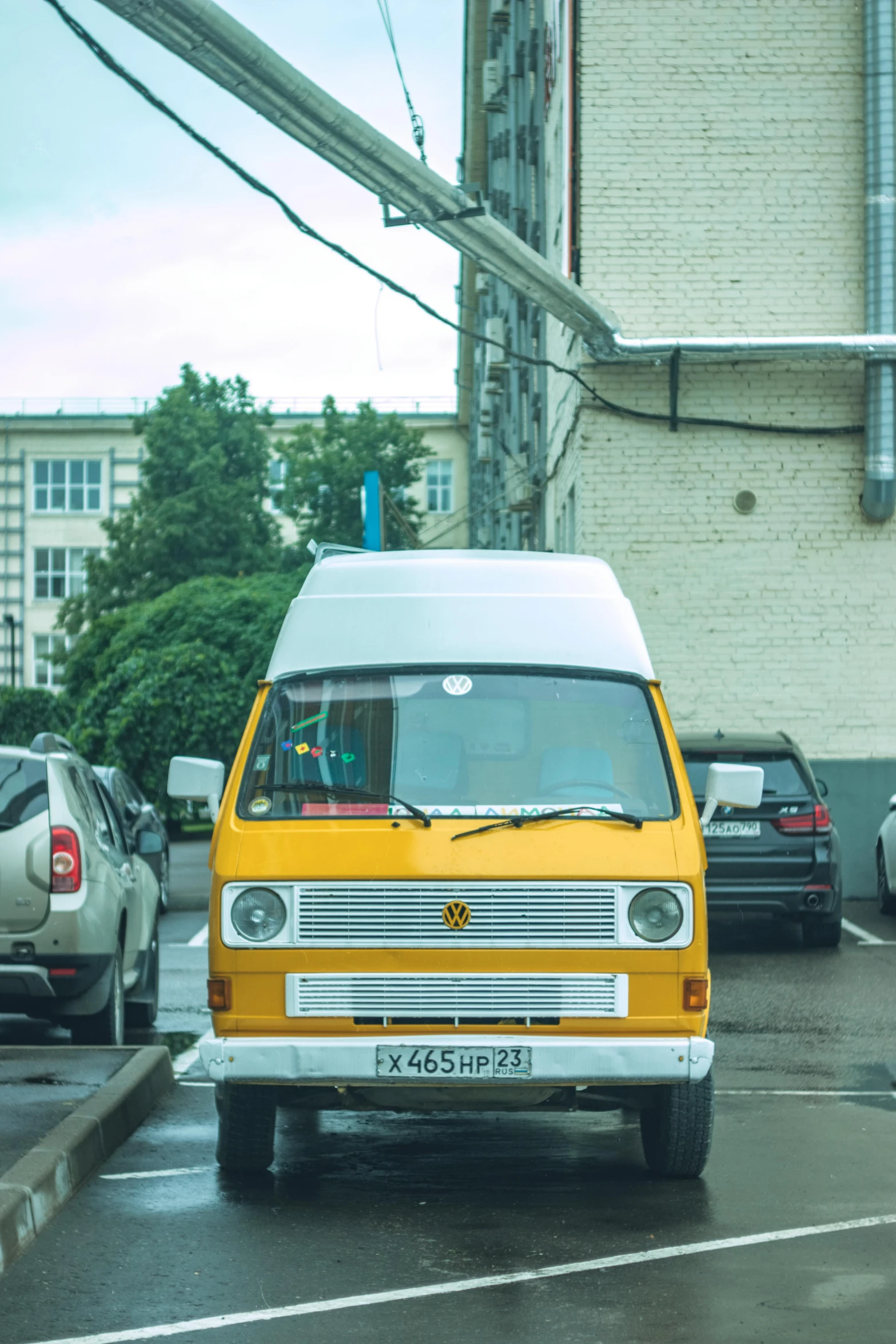 an old van drives on a wet street with cars nearby