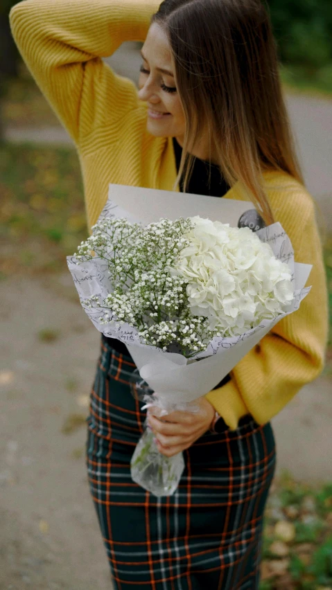 young woman holding a bunch of white flowers and a sweater