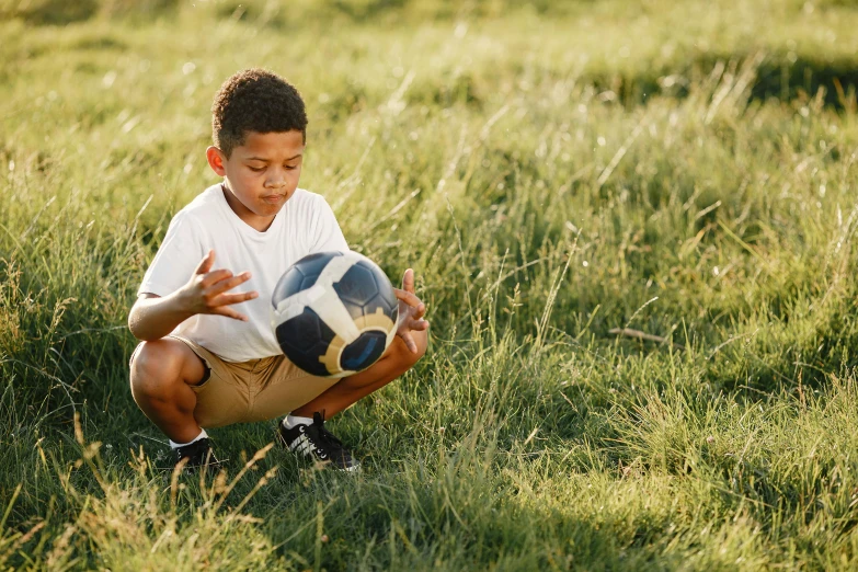 a  kneeling down playing with a soccer ball