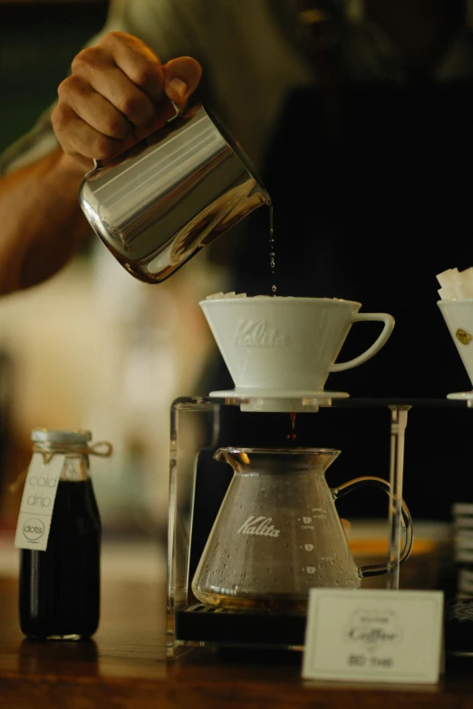 a man pours a cup with liquid from a coffee pot