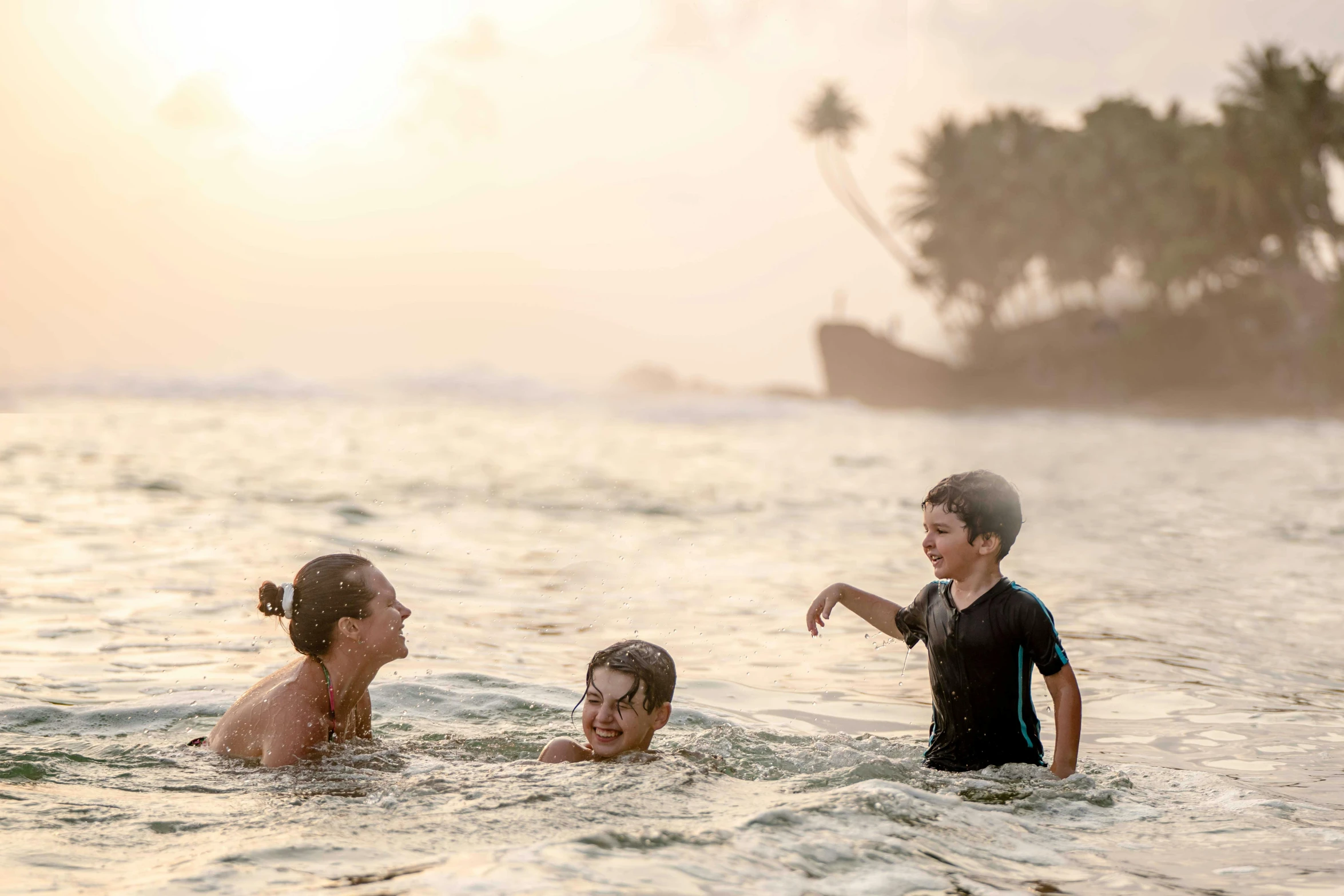 a woman standing next to a child in the ocean