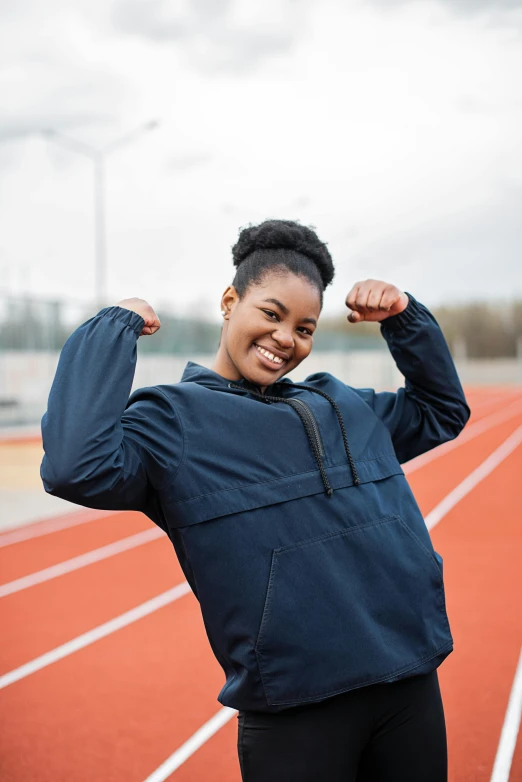 a woman flexes her muscles while standing on a track