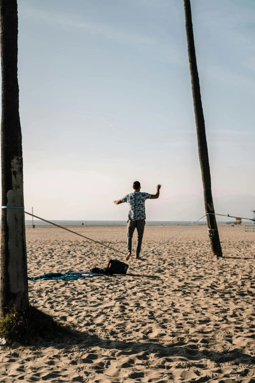 a man flying a kite on the beach next to two palm trees