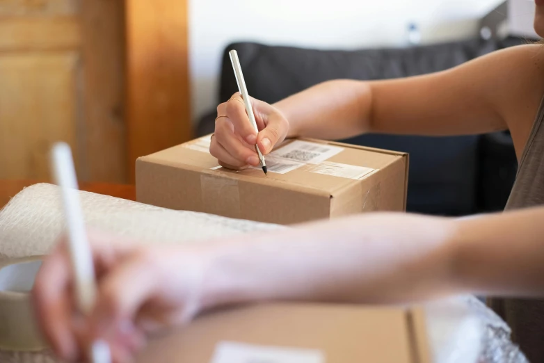 a person putting a pen on a cardboard box