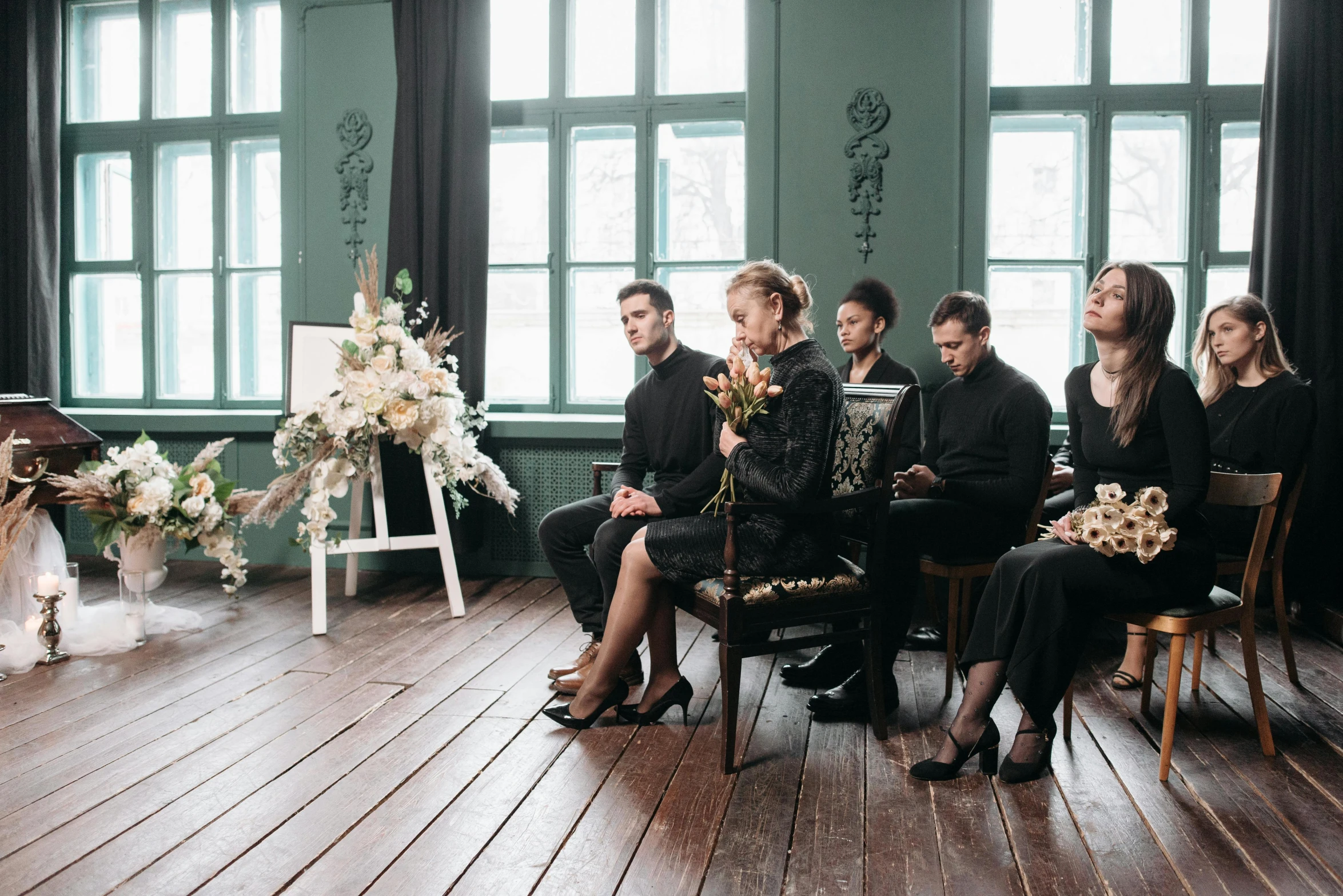 a group of people sitting on a wooden floor in front of windows