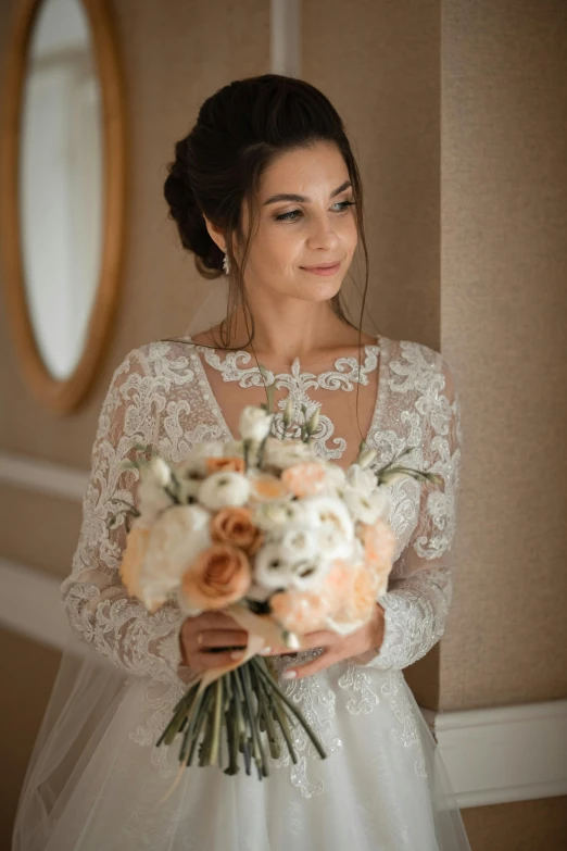 a bride holding a bouquet and standing near a mirror