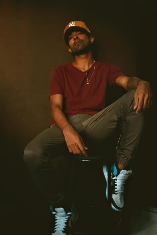 a man sitting on top of a stool wearing sneakers