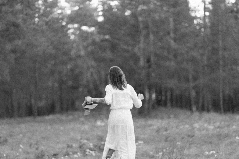 a woman in a dress walking across a field