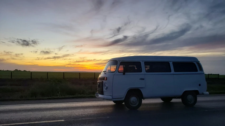 an rv drives down the road by sunset