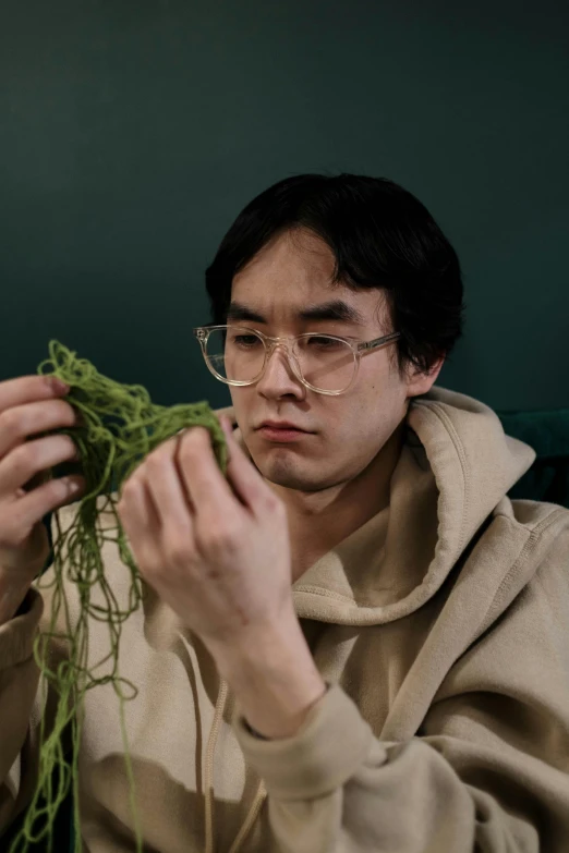 a man with glasses holding up a plant in front of him