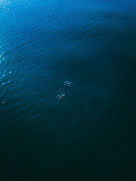 three small boats floating in the middle of the ocean