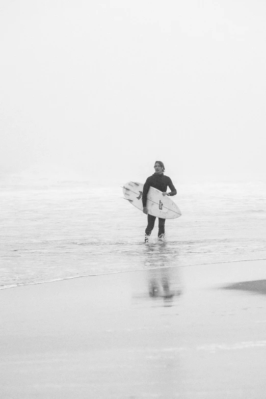 a man carrying his surfboard as he makes a break from the ocean